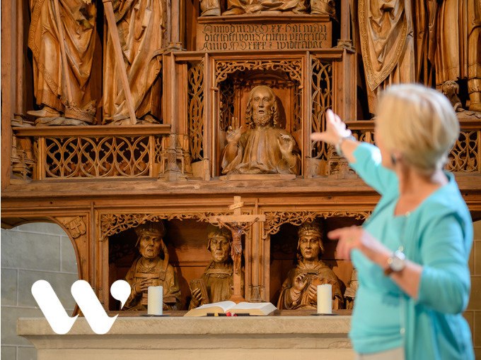Eine Frau zeigt auf den kunstvoll geschnitzten Jakobusaltar in der Winnender Schlo&szlig;kirche. Der Altar ist reich verziert mit religi&ouml;sen Figuren., &copy; Stadt Winnenden