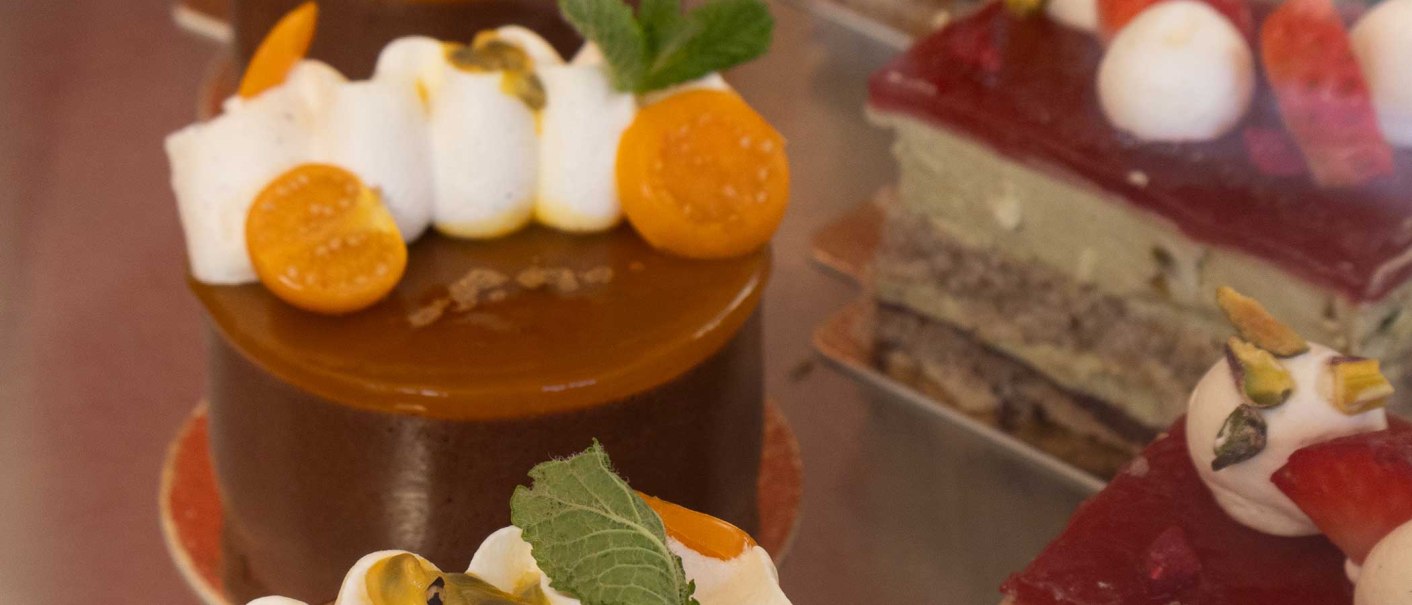 Nahaufnahme von kunstvoll dekorierten Kuchen in einer Vitrine. Verschiedene Toppings wie Früchte und Sahne sind zu sehen., © SMG Nahaufnahme von kunstvoll dekorierten Kuchen in einer Vitrine. Verschiedene Toppings wie Früchte und Sahne sind zu sehen., © SMG