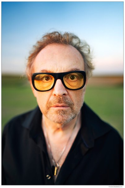 Ein Mann mit gelber Brille und ernstem Blick steht im Freien. Der Hintergrund ist unscharf, der Himmel zeigt einen sanften Farbverlauf., &copy; Konzertkreis Triangel Compagnia Compostelli e.V.