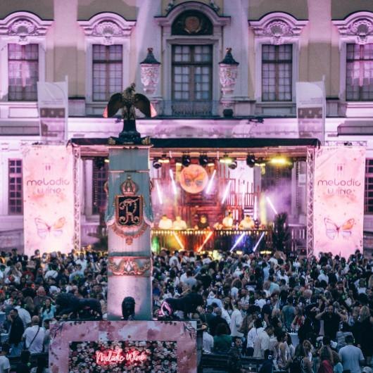 Ein lebhaftes Musikfestival mit einer gro&szlig;en Menschenmenge vor einer B&uuml;hne, die mit Lichteffekten und Bannern mit der Aufschrift 'Melodic Wine' dekoriert ist., &copy; wisio-media GmbH