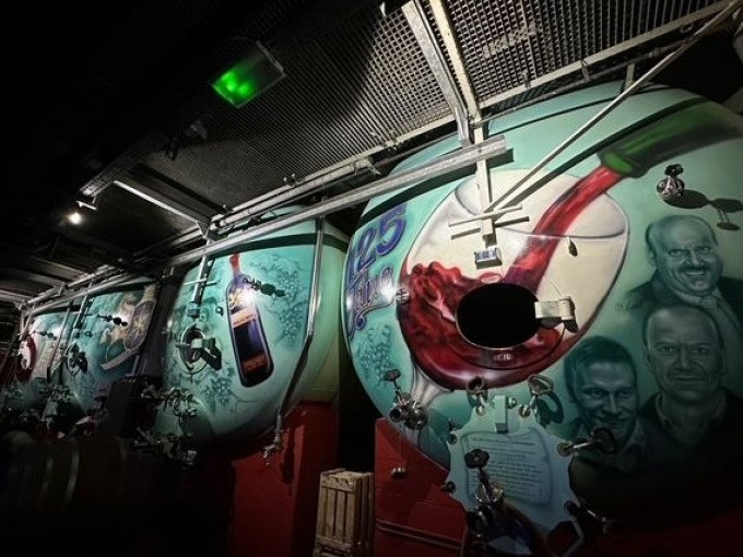 Weintanks in einem Keller, kunstvoll bemalt mit Weinmotiven und Porträts. Die Beleuchtung schafft eine stimmungsvolle Atmosphäre., © Weingenuss Stuttgart Weintanks in einem Keller, kunstvoll bemalt mit Weinmotiven und Porträts. Die Beleuchtung schafft eine stimmungsvolle Atmosphäre., © Weingenuss Stuttgart