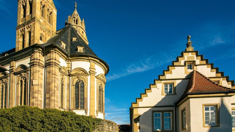 Die Gro&szlig;comburg in Schw&auml;bisch Hall zeigt beeindruckende Architektur mit einem Turm und einem Geb&auml;ude mit Treppengiebel unter klarem, blauem Himmel., &copy; Stuttgart-Marketing GmbH, Sarah Schmid
