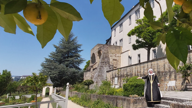 Historische Figur im Pomeranzengarten Leonberg, umgeben von Zitrusb&auml;umen und historischen Geb&auml;uden. Die Szene vermittelt eine historische Atmosph&auml;re., &copy; Stadtmarketing Leonberg