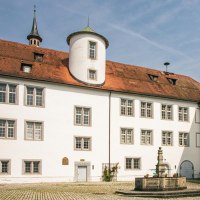 Der Innenhof von Schloss Waldenbuch zeigt wei&szlig;e Geb&auml;ude mit roten D&auml;chern und einen zentralen Brunnen. Ein blauer Himmel rundet die Szene ab., &copy; SMG, Sarah Schmid