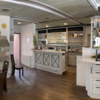 Rustikales Restaurant mit Holzmöbeln, Bar und dekorativer Wand mit "Sonnen-Besen"-Motiv. Gemütliche Atmosphäre mit Kronleuchter und Weinregal., © Weingut Zaiß