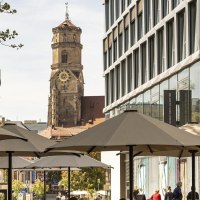 Das Dorotheenquartier in Stuttgart mit modernen Gebäuden, Sonnenschirmen und der historischen Stiftskirche im Hintergrund., © Stuttgart-Marketing GmbH, Sarah Schmid Das Dorotheenquartier in Stuttgart mit modernen Gebäuden, Sonnenschirmen und der historischen Stiftskirche im Hintergrund., © Stuttgart-Marketing GmbH, Sarah Schmid