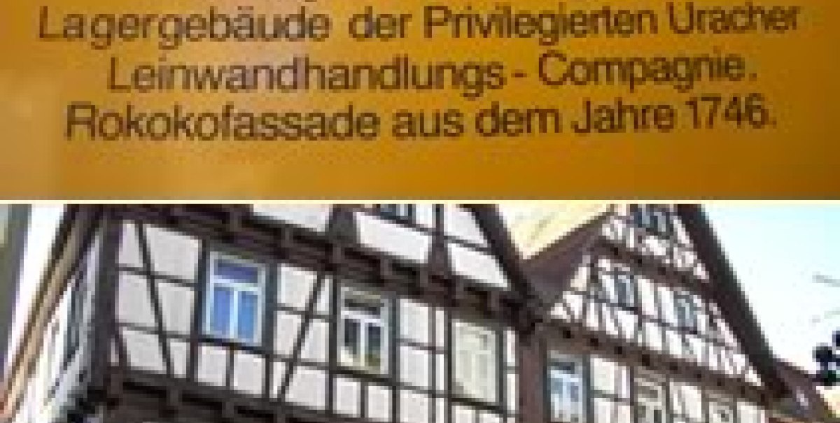 Schild mit der Aufschrift 'Manufaktur' und einem historischen Fachwerkgebäude mit Hotel-Restaurant in Urach. Schild mit der Aufschrift 'Manufaktur' und einem historischen Fachwerkgebäude mit Hotel-Restaurant in Urach.