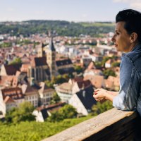 Eine Frau steht auf einer Terrasse und blickt auf die malerische Stadt Esslingen mit ihren historischen Gebäuden und grünen Hügeln., © Esslinger Stadtmarketing &amp; Tourismus GmbH