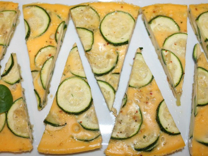 Dreieckige Zucchini-Frittata-Stücke auf einem weißen Teller, dekorativ angerichtet., © Kultweine-Kochwelten-Kunstücke - Kochschule Sonja Lenz Dreieckige Zucchini-Frittata-Stücke auf einem weißen Teller, dekorativ angerichtet., © Kultweine-Kochwelten-Kunstücke - Kochschule Sonja Lenz