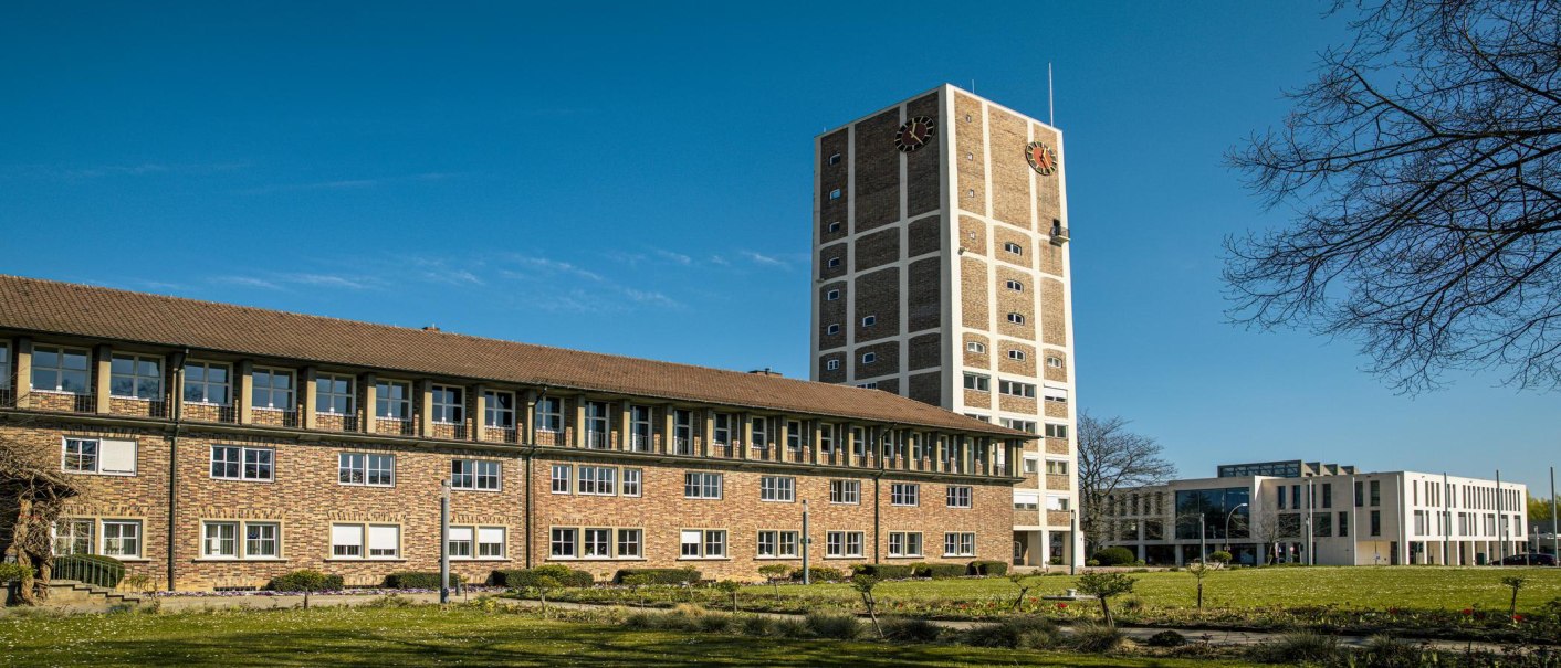 Das Rathaus Kornwestheim mit einem hohen Turm und einem modernen Anbau, umgeben von einem grünen Rasen unter blauem Himmel., © SMG, Sarah Schmid Das Rathaus Kornwestheim mit einem hohen Turm und einem modernen Anbau, umgeben von einem grünen Rasen unter blauem Himmel., © SMG, Sarah Schmid