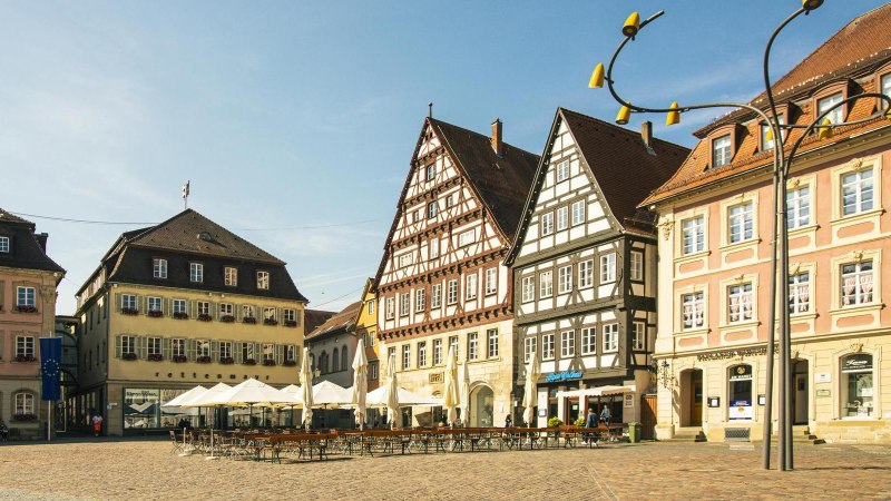 Historische Gebäude am Marktplatz in Schwäbisch Gmünd, darunter Fachwerkhäuser und das Rathaus. Sonnenschirme und leere Tische im Vordergrund., © Stuttgart-Marketing GmbH, Sarah Schmid