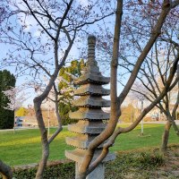 Eine Steinpagode steht in einem Garten, umgeben von blühenden Bäumen und grünem Rasen. Der Himmel ist klar und blau., © SMG Eine Steinpagode steht in einem Garten, umgeben von blühenden Bäumen und grünem Rasen. Der Himmel ist klar und blau., © SMG