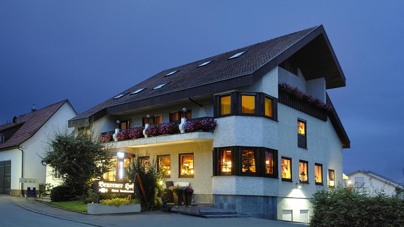 Beleuchtetes Gebäude bei Nacht mit Blumen auf dem Balkon und einem Schild "Beurener Hof". Der Himmel ist dunkelblau., © Hotel & Restaurant Beurener Hof Beleuchtetes Gebäude bei Nacht mit Blumen auf dem Balkon und einem Schild "Beurener Hof". Der Himmel ist dunkelblau., © Hotel & Restaurant Beurener Hof