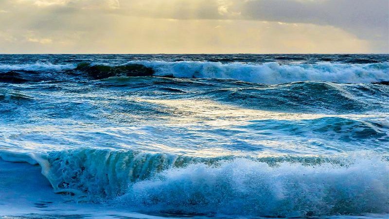 Dynamische Meereswellen unter einem bewölkten Himmel, durch den Sonnenstrahlen brechen. Die Szene vermittelt eine ruhige und zugleich kraftvolle Atmosphäre., © Backnang Dynamische Meereswellen unter einem bewölkten Himmel, durch den Sonnenstrahlen brechen. Die Szene vermittelt eine ruhige und zugleich kraftvolle Atmosphäre., © Backnang