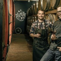Zwei Männer in einem Weinkeller mit Holzfässern, halten Weingläser. Im Hintergrund ist ein Logo an der Wand., © Weingut Aldinger Zwei Männer in einem Weinkeller mit Holzfässern, halten Weingläser. Im Hintergrund ist ein Logo an der Wand., © Weingut Aldinger