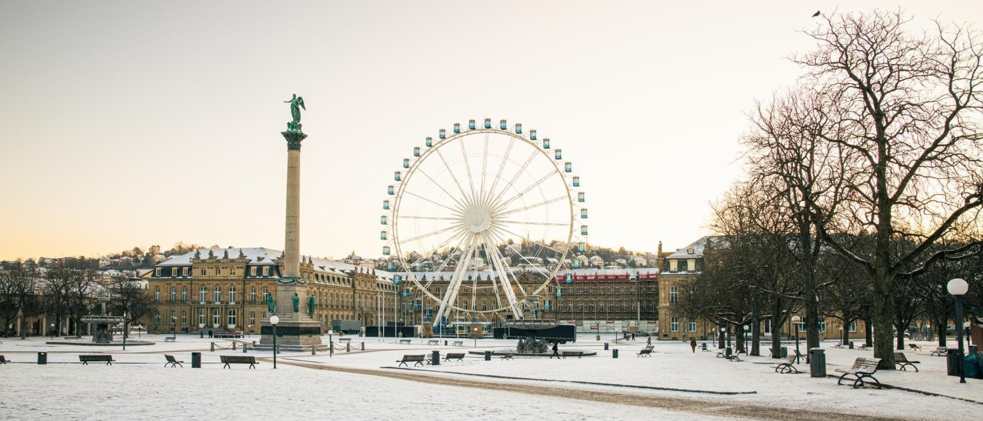 Winterlicher Schlossplatz in Stuttgart mit schneebedecktem Boden, einer hohen Säule und einem großen Riesenrad vor einem Schloss, im Hintergrund., © Stuttgart-Marketing GmbH, Sarah Schmid Winterlicher Schlossplatz in Stuttgart mit schneebedecktem Boden, einer hohen Säule und einem großen Riesenrad vor einem Schloss, im Hintergrund., © Stuttgart-Marketing GmbH, Sarah Schmid