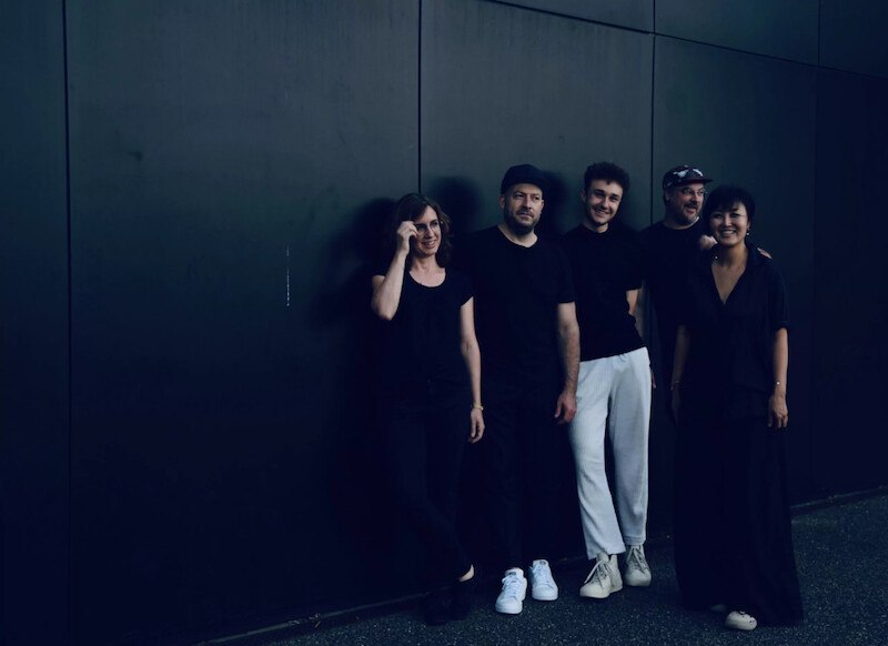 Fünf Personen in schwarzer Kleidung stehen lächelnd vor einer dunklen Wand. Sie wirken entspannt und freundlich., © Jazzclub Schwäbisch Hall e.V. Fünf Personen in schwarzer Kleidung stehen lächelnd vor einer dunklen Wand. Sie wirken entspannt und freundlich., © Jazzclub Schwäbisch Hall e.V.