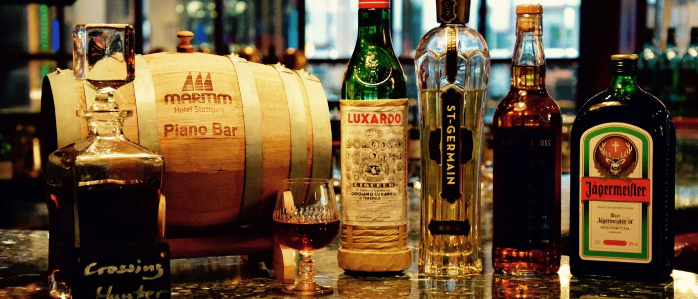 Eine Bar mit Spirituosenflaschen wie Luxardo, St-Germain und J&auml;germeister neben einem Holzfass der Maritim Hotel Stuttgart Piano Bar., &copy; Maritim Hotels