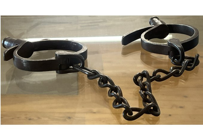 Alte Metallfesseln mit einer Kette liegen auf einem Holztisch. Sie erinnern an historische Methoden der Gefangennahme., &copy; Stadt Besigheim