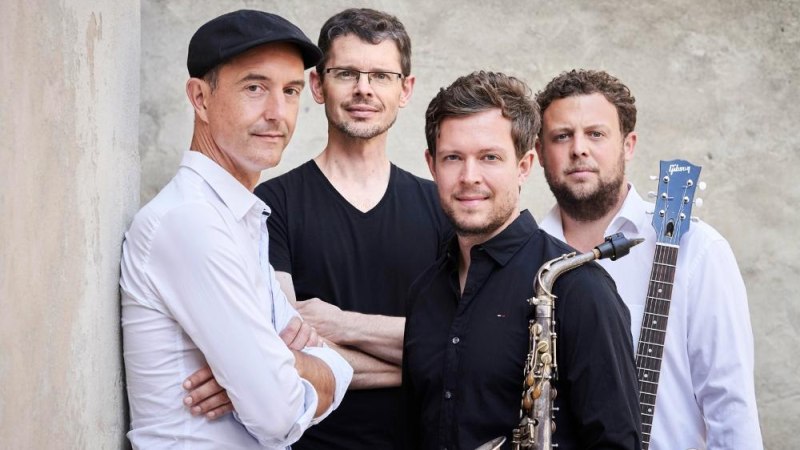 Vier Männer posieren vor einer Wand, einer mit Saxophon, ein anderer mit Gitarre. Sie tragen lässige Kleidung und blicken in die Kamera., © Foto Kaupo Kikkas Vier Männer posieren vor einer Wand, einer mit Saxophon, ein anderer mit Gitarre. Sie tragen lässige Kleidung und blicken in die Kamera., © Foto Kaupo Kikkas
