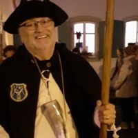 Ein Mann in Nachtw&auml;chterkleidung mit Hut und Stab l&auml;chelt in die Kamera. Im Hintergrund sind Menschen und ein beleuchtetes Geb&auml;ude zu sehen., &copy; WTM GmbH Waiblingen