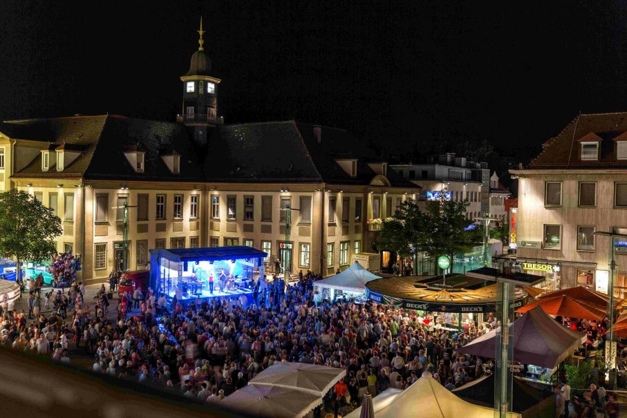 Nachtaufnahme des Göppinger Stadtfests mit beleuchteter Bühne und großer Menschenmenge vor historischen Gebäuden.
