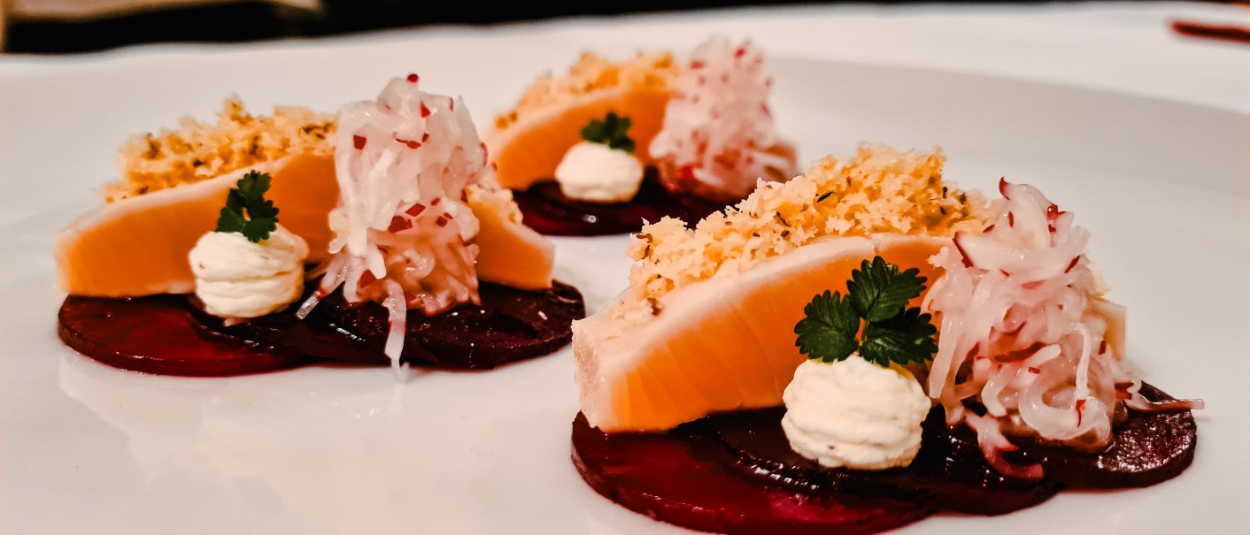 Gourmetgericht mit eingelegter Forelle, Rote Bete, Sahne und Kräutern auf einem weißen Teller kunstvoll angerichtet., © Hupperts Gourmetgericht mit eingelegter Forelle, Rote Bete, Sahne und Kräutern auf einem weißen Teller kunstvoll angerichtet., © Hupperts