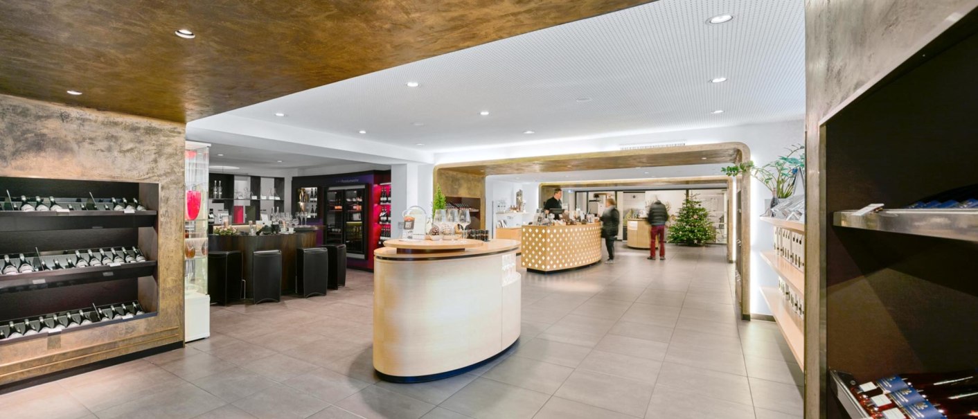 Moderne Vinothek mit eleganter Einrichtung, Weinregalen und einer zentralen Theke. Ein Weihnachtsbaum steht im Hintergrund., &copy; Weinmanufaktur Stuttgart