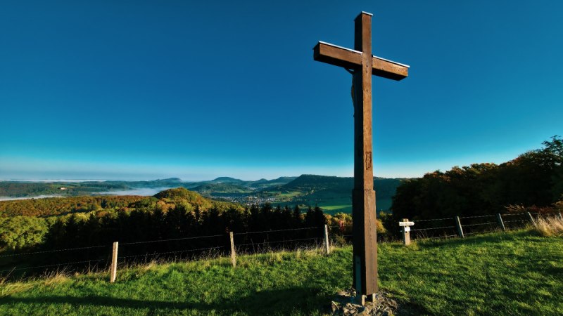 Holzkreuz auf Wiese mit Blick auf hügelige Landschaft und blauem Himmel., © Landkreis Göppingen