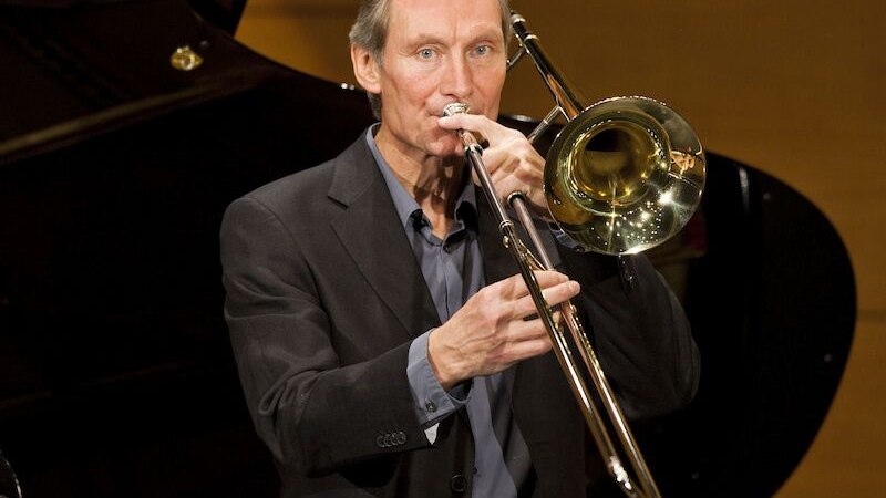 Ein Mann in einem Anzug spielt Posaune auf einer Bühne. Im Hintergrund ist ein Flügel zu sehen. Der Fokus liegt auf dem Musiker und seinem Instrument., © Stadt Böblingen - Amt für Kultur Ein Mann in einem Anzug spielt Posaune auf einer Bühne. Im Hintergrund ist ein Flügel zu sehen. Der Fokus liegt auf dem Musiker und seinem Instrument., © Stadt Böblingen - Amt für Kultur