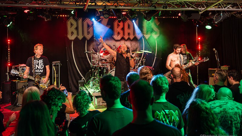 Eine Rockband namens Big Balls performt auf einer Bühne vor einem begeisterten Publikum. Der Sänger hebt die Arme, während die Band spielt., © Interessengemeinschaft Kultur Sindelfingen / Böblingen e.V.