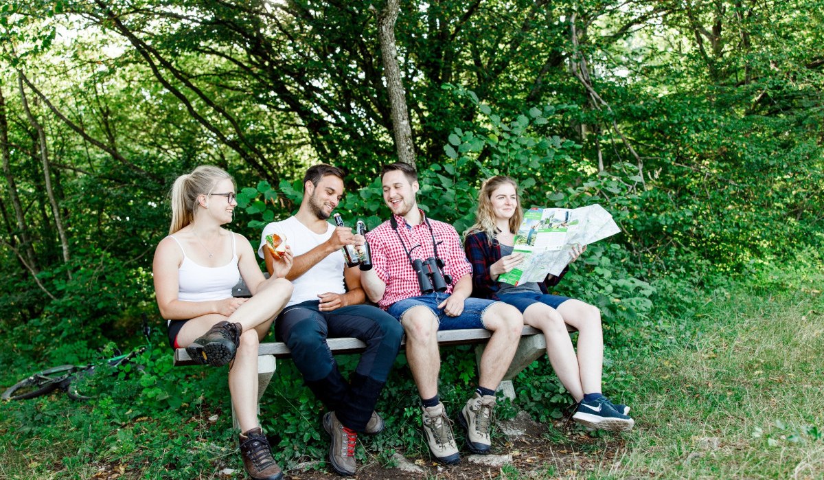 Vier Personen sitzen auf einer Bank im Wald, trinken und schauen eine Karte an. Sie wirken entspannt und genießen die Natur., © Landkreis Göppingen Vier Personen sitzen auf einer Bank im Wald, trinken und schauen eine Karte an. Sie wirken entspannt und genießen die Natur., © Landkreis Göppingen