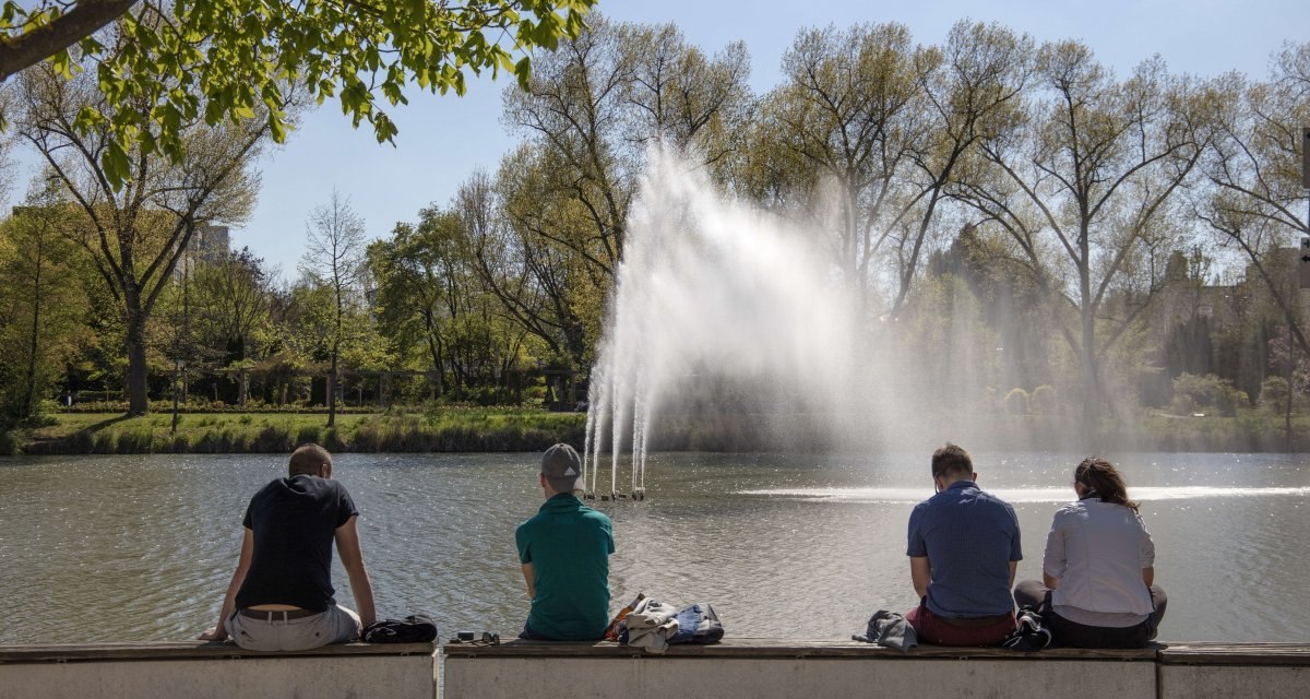 Vier Personen sitzen auf einer Bank am See, im Hintergrund ein Springbrunnen und B&auml;ume., &copy; Stuttgart Marketing GmbH Achim Mende