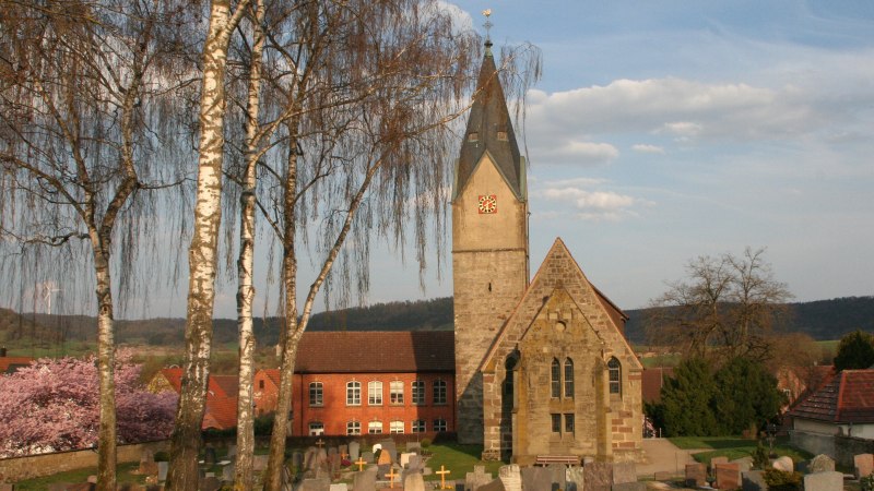 Die Martinskirche in Ottendorf mit ihrem markanten Turm, umgeben von einem Friedhof und bl&uuml;henden B&auml;umen im Fr&uuml;hling., &copy; Petra Natzkowski