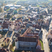Luftaufnahme von Gaildorf mit Fachwerkhäusern, Kirche und umliegenden Gebäuden. Die Stadt ist von grünen Feldern umgeben., © Stadt Gaildorf