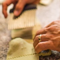 Hände schneiden frische Pasta mit einem Teigrädchen auf einer Arbeitsfläche., © La Signora Moro Hände schneiden frische Pasta mit einem Teigrädchen auf einer Arbeitsfläche., © La Signora Moro