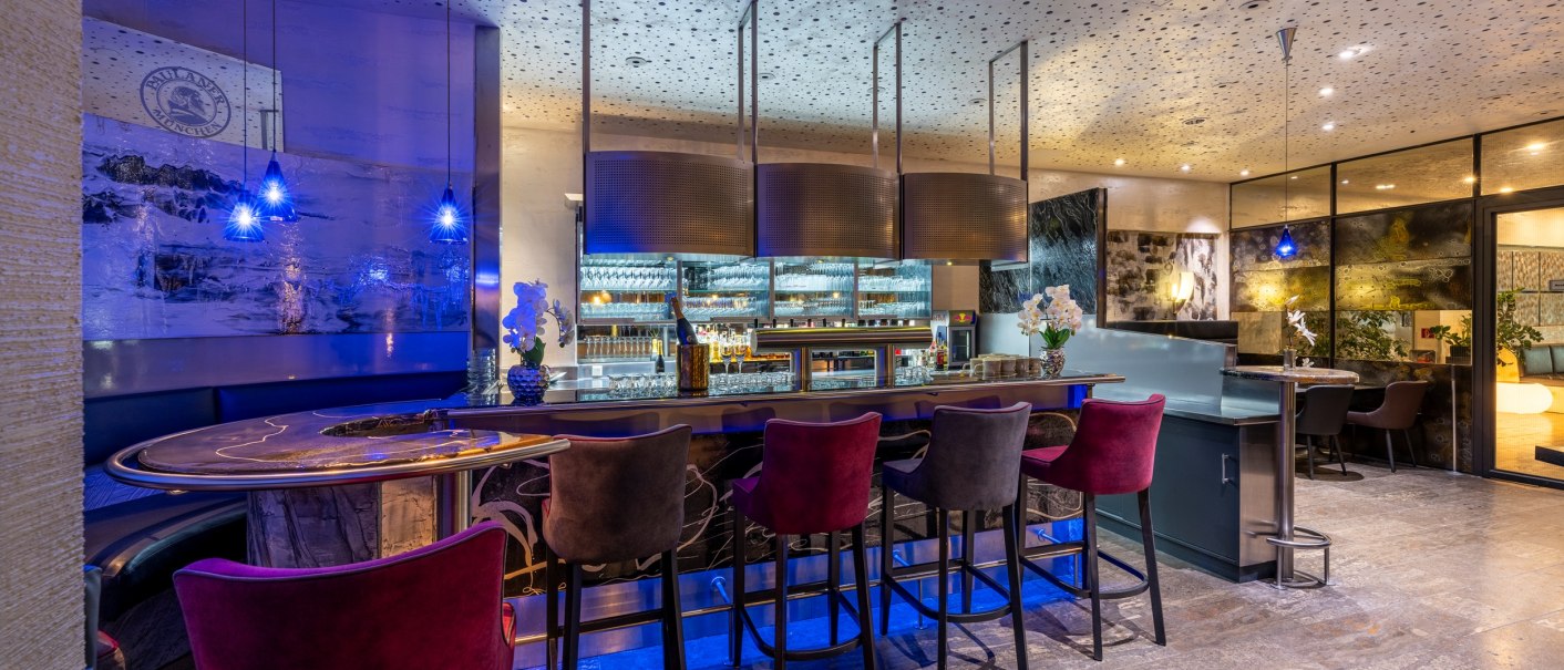 Eine stilvolle Bar mit blauer Beleuchtung, eleganten Barhockern und dekorativen Elementen. Die Decke ist mit kleinen Lichtern verziert., © Plaza Residence Stuttgart-Ditzingen Eine stilvolle Bar mit blauer Beleuchtung, eleganten Barhockern und dekorativen Elementen. Die Decke ist mit kleinen Lichtern verziert., © Plaza Residence Stuttgart-Ditzingen