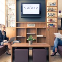 Zwei Frauen sitzen in einer modernen Lobby. Eine arbeitet am Laptop, die andere liest eine Zeitung. Im Hintergrund ein Regal und ein Bildschirm mit Logo., © Mercure Hotel Stuttgart Gerlingen