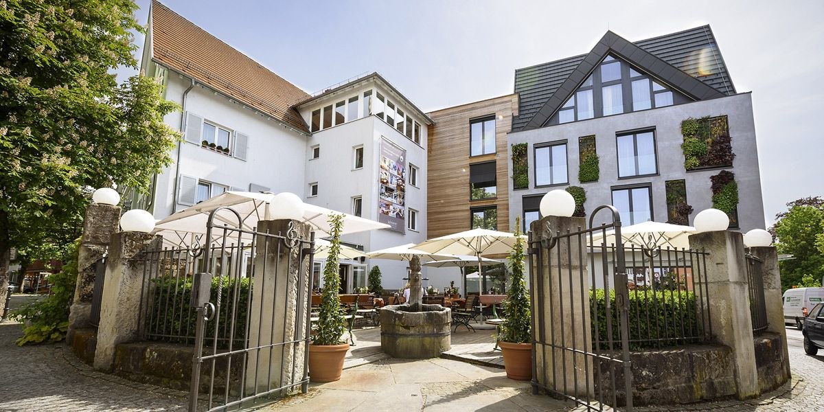 Hotel-Restaurant Schwanen mit moderner Fassade, Terrasse mit Sonnenschirmen und dekorativen Pflanzen. Historisches Tor im Vordergrund., &copy; Hotel-Restaurant Schwanen