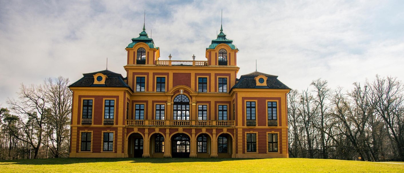 Schloss Favorite in Ludwigsburg, ein barockes Gebäude mit gelben und roten Fassaden, umgeben von Bäumen und Rasen., © Stuttgart-Marketing GmbH, Sarah Schmid