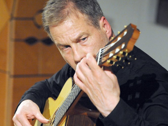 Ein Gitarrist spielt konzentriert auf einer klassischen Gitarre. Er trägt ein schwarzes Hemd und ist in eine musikalische Darbietung vertieft., © Stadt Murrhardt Ein Gitarrist spielt konzentriert auf einer klassischen Gitarre. Er trägt ein schwarzes Hemd und ist in eine musikalische Darbietung vertieft., © Stadt Murrhardt