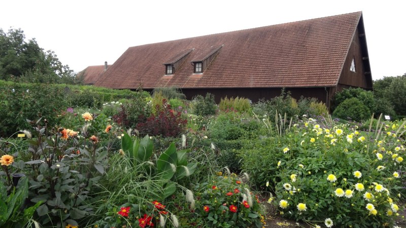 Bunter Blumengarten vor einem traditionellen Bauernhaus mit rotem Ziegeldach und Holzwänden., © Nürtingen - Stuttgart-Marketing GmbH Bunter Blumengarten vor einem traditionellen Bauernhaus mit rotem Ziegeldach und Holzwänden., © Nürtingen - Stuttgart-Marketing GmbH