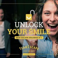 Frau jubelt mit geballten Fäusten, im Hintergrund weitere feiernde Personen. Text: "Unlock Your Smile" und "TeamEscape"., © TeamEscape Stuttgart