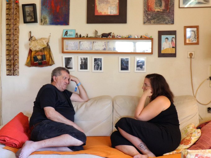 Zwei Personen sitzen auf einem Sofa in einem gem&uuml;tlich dekorierten Raum und unterhalten sich. An der Wand h&auml;ngen Bilder und Dekorationen., &copy; Kunsthalle G&ouml;ppingen