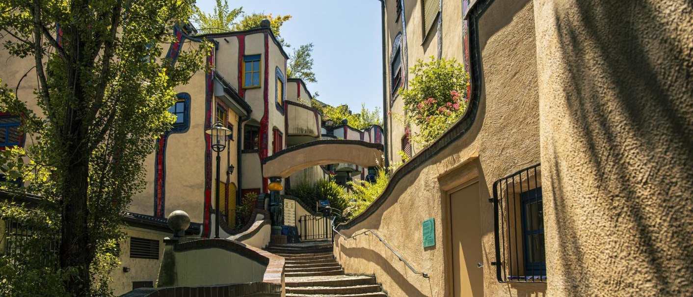 Das Hundertwasserhaus in Plochingen zeigt seine charakteristische, bunte und wellenförmige Architektur mit üppiger Begrünung und geschwungenen Wegen., © SMG, Sarah Schmid Das Hundertwasserhaus in Plochingen zeigt seine charakteristische, bunte und wellenförmige Architektur mit üppiger Begrünung und geschwungenen Wegen., © SMG, Sarah Schmid