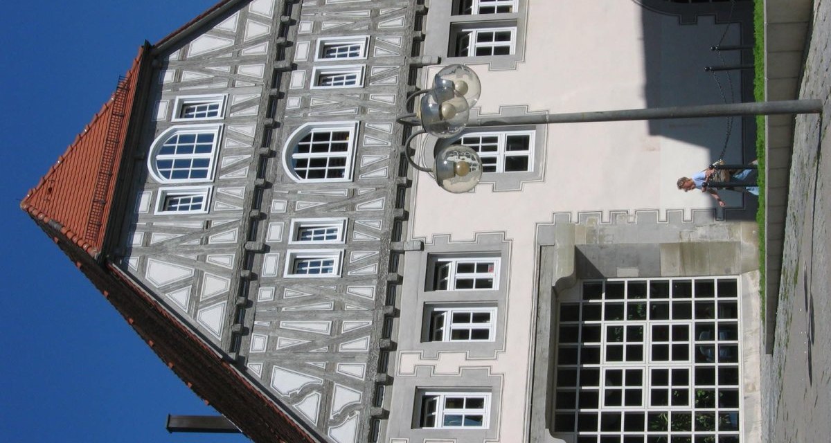 Fachwerkgebäude mit großen Fenstern und rotem Dach. Eine Person geht auf dem Gehweg entlang. Der Himmel ist klar und blau., © Land der 1000 Hügel - Kraichgau-Stromberg Fachwerkgebäude mit großen Fenstern und rotem Dach. Eine Person geht auf dem Gehweg entlang. Der Himmel ist klar und blau., © Land der 1000 Hügel - Kraichgau-Stromberg