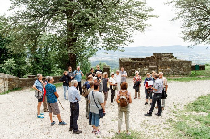 Gruppe bei einer Führung auf dem Hohenstaufen, umgeben von Bäumen und alten Mauern, mit Blick auf die Landschaft., © Stadt Göppingen Gruppe bei einer Führung auf dem Hohenstaufen, umgeben von Bäumen und alten Mauern, mit Blick auf die Landschaft., © Stadt Göppingen