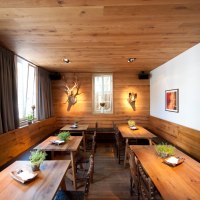 Ein gem&uuml;tliches Restaurant mit Holztischen, Pflanzen auf den Tischen und dekorativen Elementen an den W&auml;nden. Holzw&auml;nde und -decke schaffen eine warme Atmosph&auml;re., &copy; Ruthenberg&Schlatter GbR