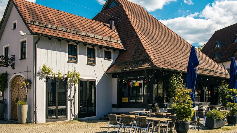 Traditionelles Gebäude mit Ziegeldach und Restaurant auf dem Kelterplatz in Metzingen. Sonnenschirme und Tische im Freien, umgeben von Pflanzen., © Stuttgart-Marketing GmbH, Sarah Schmid Traditionelles Gebäude mit Ziegeldach und Restaurant auf dem Kelterplatz in Metzingen. Sonnenschirme und Tische im Freien, umgeben von Pflanzen., © Stuttgart-Marketing GmbH, Sarah Schmid