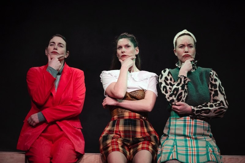 Drei Frauen in verschiedenen Outfits sitzen nachdenklich auf einer Bank vor schwarzem Hintergrund., © Kulturhaus Schwanen Drei Frauen in verschiedenen Outfits sitzen nachdenklich auf einer Bank vor schwarzem Hintergrund., © Kulturhaus Schwanen